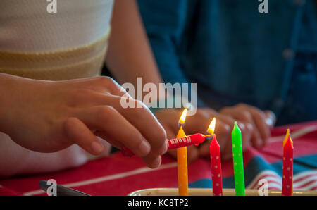 A girl lighting birthday candle on a cake Stock Photo