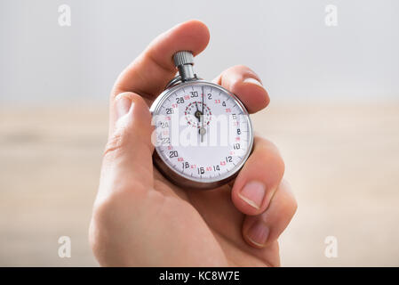 Close-up Of Businessman Holding Stopwatch In Office Stock Photo