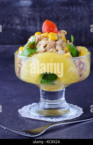 Salad with chiken fillet, pineapple, mushrooms, walnuts in a glass on a grey abstract background. Healthy eating concept. Russian traditional foo Stock Photo
