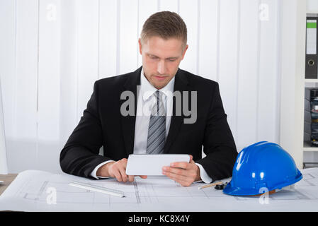 Close-up Of Young Male Architecture Using Digital Tablet Over Blueprint In Office Stock Photo