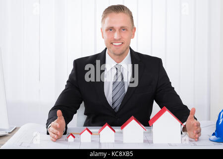 Young Happy Male Architect Working With House Models On Blueprints In Office Stock Photo