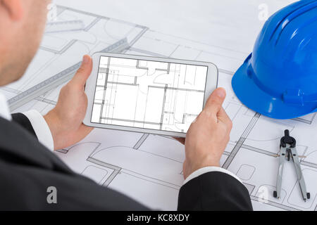 Male Architect Analyzing Blue Print On Digital Tablet In Office Stock Photo