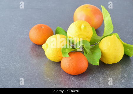 Citrus collection Fresh oranges, lemons and mandarins on a grey abstract background. Mediterranean lifestyle. Healthy food. Stock Photo