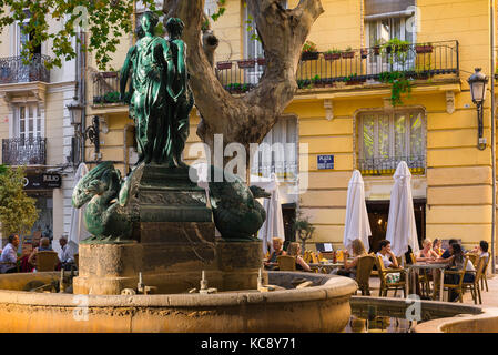 Valencia street cafe, people relax at cafe tables near a 19th century fountain in the Plaza Rodrigo Botet in the centre of Valencia, Spain. Stock Photo