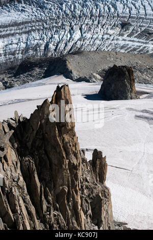 Lone rock climber on top of mountain pinnacle overlooking Glacier du Argentiere in summer Stock Photo