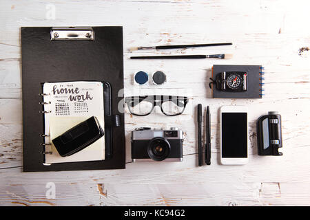 Desk with smartphone and school supplies. Studio shot on white wooden background. Stock Photo