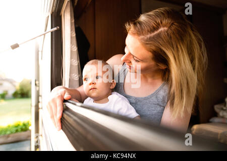 Beautiful young mother and her baby son in a camper van on a summer day Stock Photo