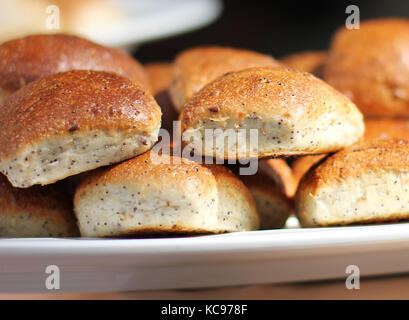 Freshly baked wheat buns with poppy seeds on the white plate Stock Photo