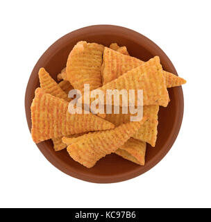 Top view of a small red clay bowl filled with cheese flavored cone shaped corn chips isolated on a white background. Stock Photo