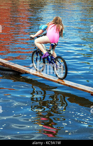 Czech festival, A cyclist on a wooden footbridge tries to cross the pond, All-year competition in a small village Blazkov, Czech Republic Stock Photo