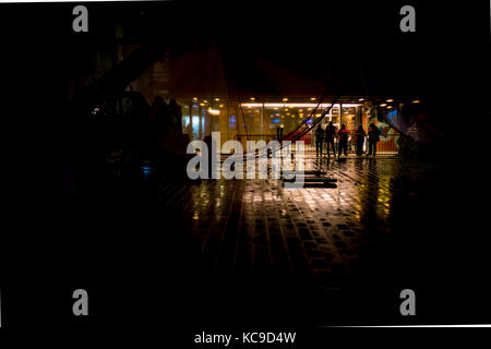 Silhouettes of people standing outside a theatre on a rainy night in autumn in the UK Stock Photo