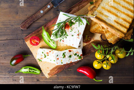 Cheese with vegetables and toasted bread on natural wooden board Stock Photo