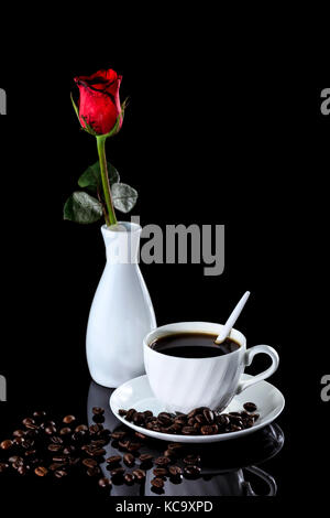 Composition of coffee and red rose on a black reflective background. Studio shot Stock Photo