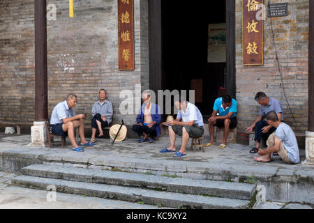 Group of senior Chinese men relaxing, talking and smoking in Jiuxian village, Yangshuo County, Guangxi, China, Asia. Old friends having fun with leisu Stock Photo