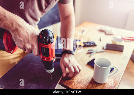 Man drilling laminate with power drill on the table Stock Photo