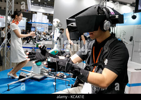 A booth assistant interacts with a master-slave robot TELESAR V while a man is controlling it using virtual reality technology at CEATEC Japan 2017 on October 3, 2017, Chiba, Japan. The Combined Exhibition of Advanced Technologies (CEATEC) Japan is a technology exhibition showing the latest trends and developments. This year there are 667 companies and organizations from 23 countries exhibiting in various fields such as robotics, Virtual Reality (VR) and Artificial Intelligence (AI). CEATEC runs until October 6 at the International Convention Complex Makuhari Messe in Chiba. (Photo by Rodrigo Stock Photo