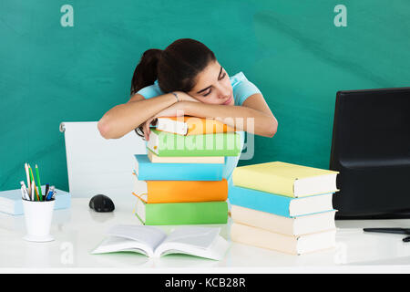 Close-up Of A Young Woman Resting On Pile Of Books In A Classroom Stock Photo