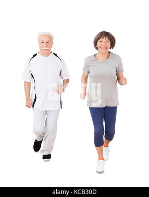 Portrait Of Senior Couple Jogging Over White Background Stock Photo