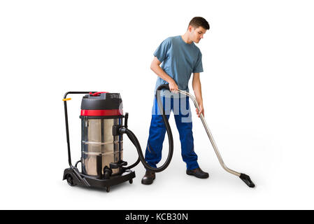 Young Man Cleaning Floor Using Vacuum Cleaner On White Background Stock Photo