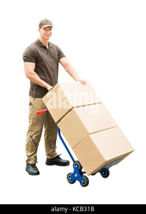 Portrait Of A Delivery Man Holding Trolley With Cardboard Boxes On White Background Stock Photo