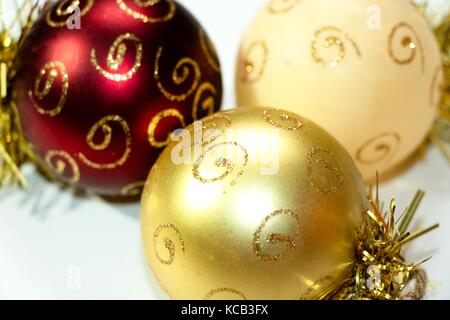 Three multi-colored Christmas decorations in the shape of a balloon, painted with gold patterns. A composition of New Year's toys on a white backgroun Stock Photo