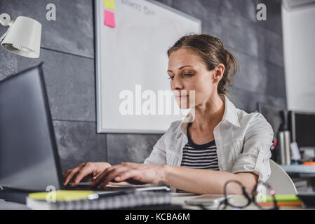 Woman wearing white shirt using laptop at office Stock Photo