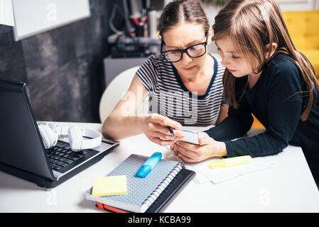 Mother and daughter using smart phone at home office Stock Photo