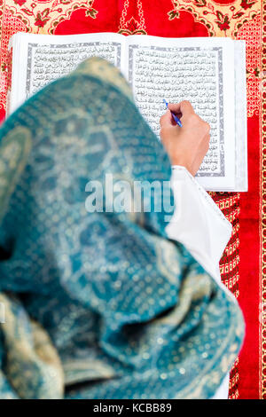 Asian Muslim woman studying Koran or Quran Stock Photo