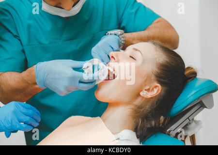 Doctor dentist puts the retractor to the patient.