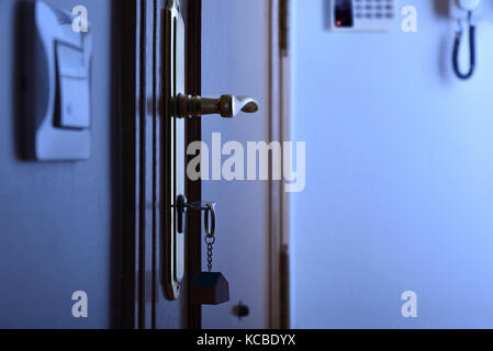 Entrance door with keys in the lock to the night. Concept of security in housing. Lateral view Stock Photo