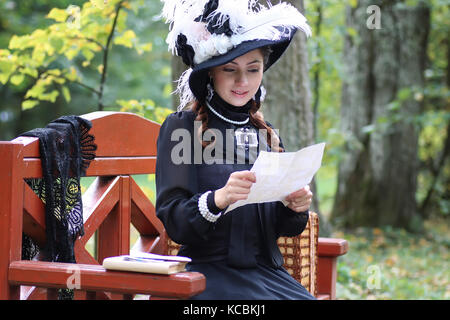 girl in retro dress past century read letter on the bench Stock Photo