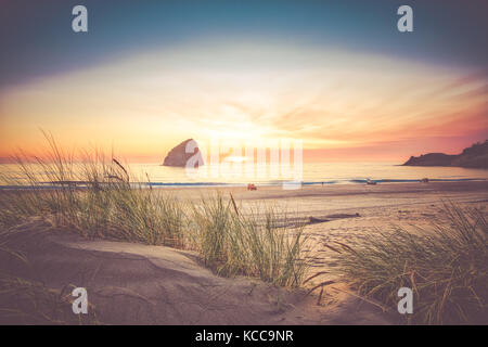 The sun sets over Haystack Rock at Cape Kiwanda, Pacific City, Oregon, USA Stock Photo