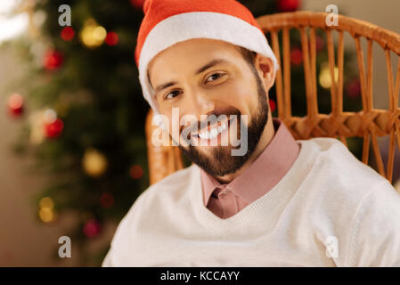 Handsome man in Santa hat smiling at camera Stock Photo