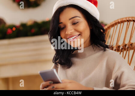 Smiling woman in Santa hat sending text messages Stock Photo