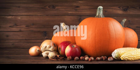 Autumn harvest still life with pumpkins, apples, hazelnut, corn, ginger, onion and cinnamon on wooden background Stock Photo