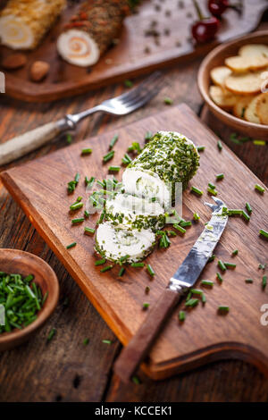 Cheese with chives on wooden cutting board Stock Photo
