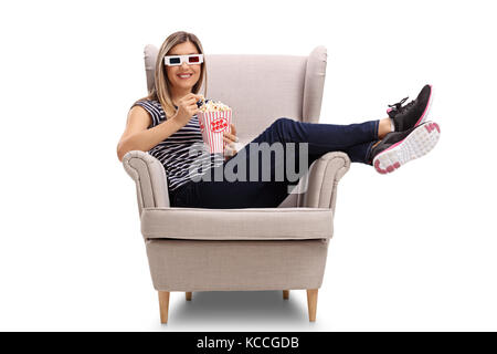 Young woman with 3D glasses and popcorn sitting in an armchair and looking at the camera isolated on white background Stock Photo