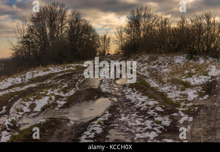 Autumnal landscape with extremely dirty road leading to small Ukrainian village Shpilivka in Sumskaya oblast, Ukraine Stock Photo