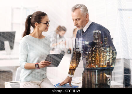 Pleasant beautiful woman talking with his experienced colleague in the office Stock Photo