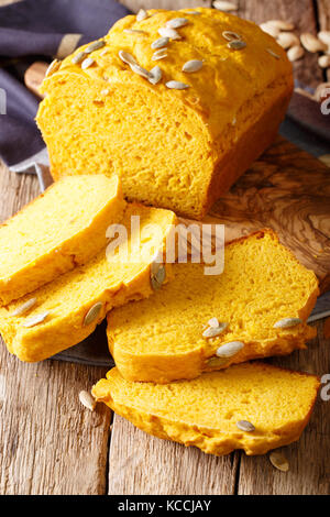Sliced pumpkin bread loaf sitting on wooden cutting board close-up on the table. Vertical Stock Photo