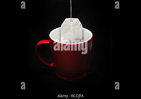 tea bag box in a red mug on a black isolated background Stock Photo