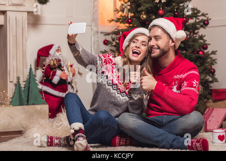 couple in santa hats taking selfie Stock Photo