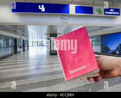 Person holding generic passport in airport passport control area, digital composite. Stock Photo