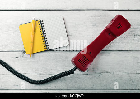 phone handset and blank notebook on white wood table Stock Photo