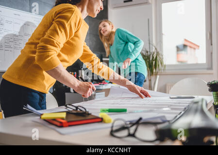 Two business woman checking blueprints in the office Stock Photo