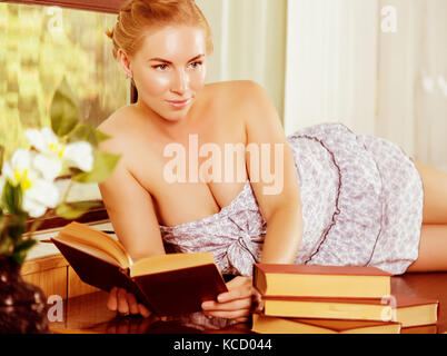 young woman reads a book lying on a desk in front of a window. old style, lolita concept Stock Photo