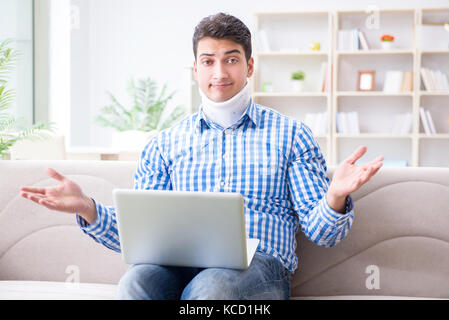 Man freelancer in a cervical collar neck brace working from home Stock Photo