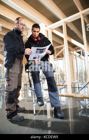 Low angle view of male carpenters looking at plan while working at construction site Stock Photo