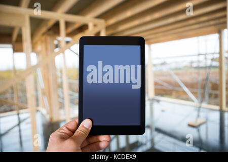 Closeup of hand holding digital tablet with blank screen at construction site Stock Photo