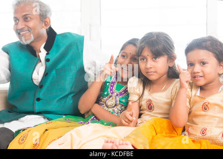 Portrait of Indian family watching tv at home. Happy Asian father and children indoors lifestyle. Stock Photo